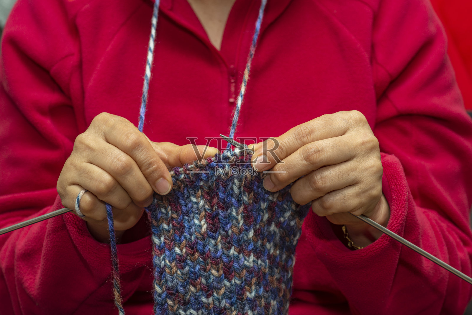 一位中年妇女正在家里用彩绳编织。照片摄影图片