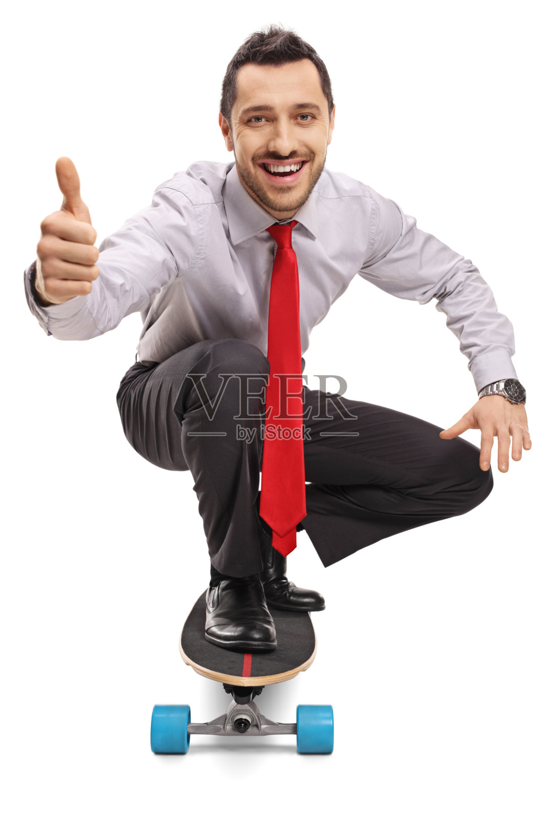 年轻的商人跪着，骑着滑板，竖起大拇指照片摄影图片