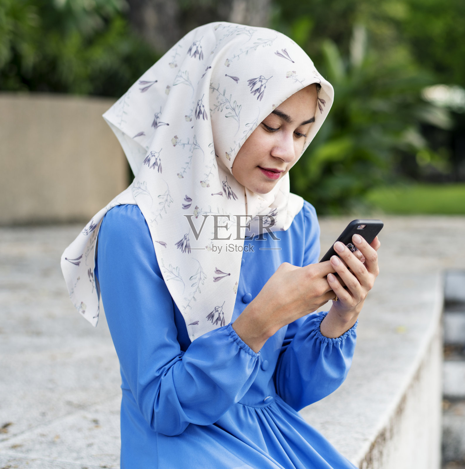 一个穆斯林女孩在公园里用智能手机照片摄影图片
