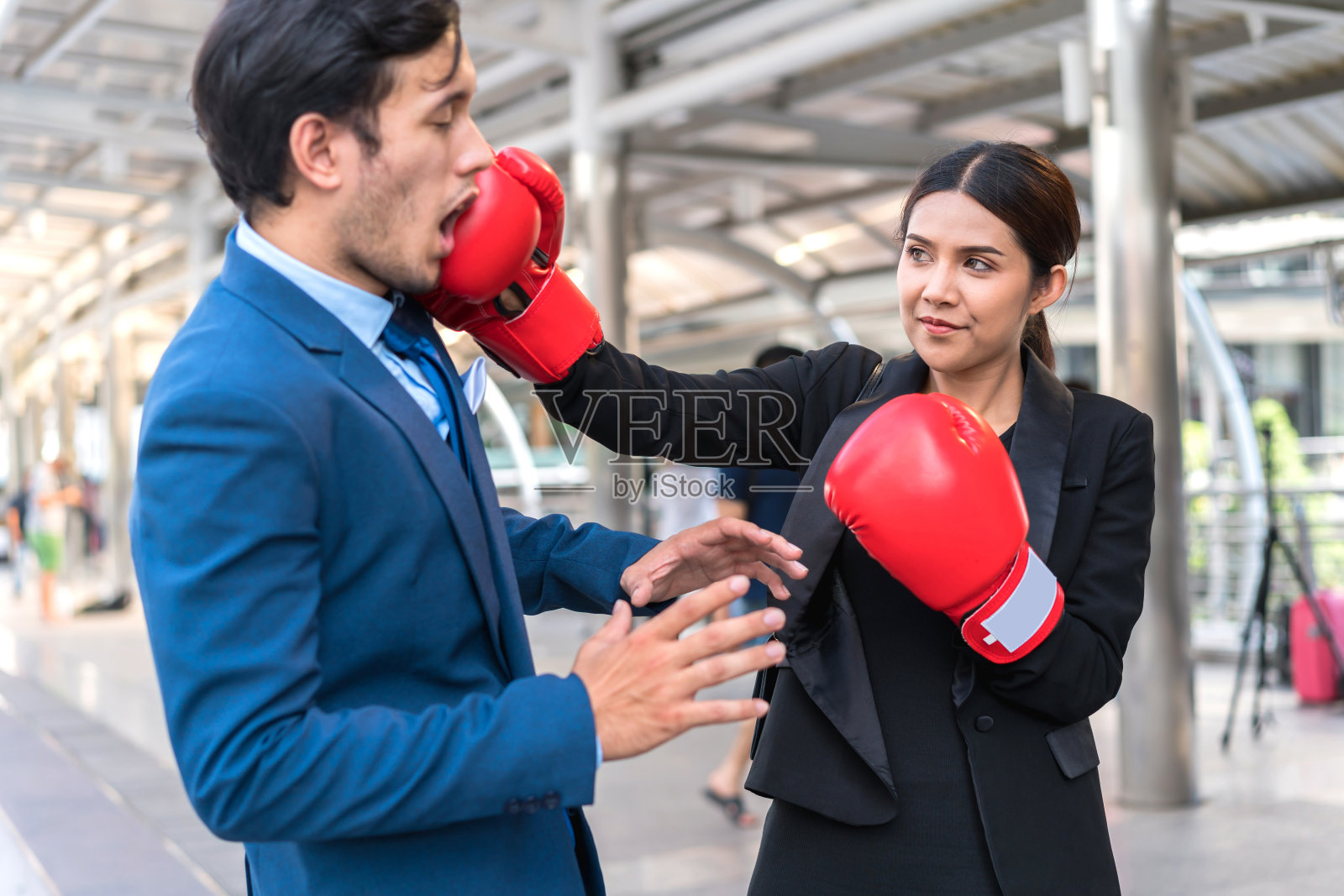 商人们戴着红手套打架。女人给男人一拳。商业竞争的概念。照片摄影图片