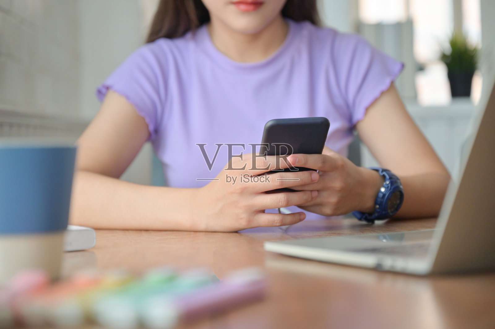 一个女孩在学习间隙和朋友用智能手机聊天。照片摄影图片