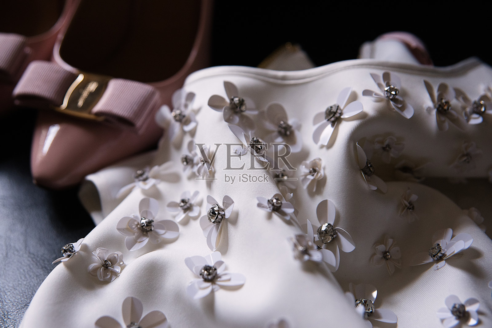 旁边是一件白色的装饰有花朵的布料裙子和粉色的新娘鞋，还有新娘服装的细节照片摄影图片