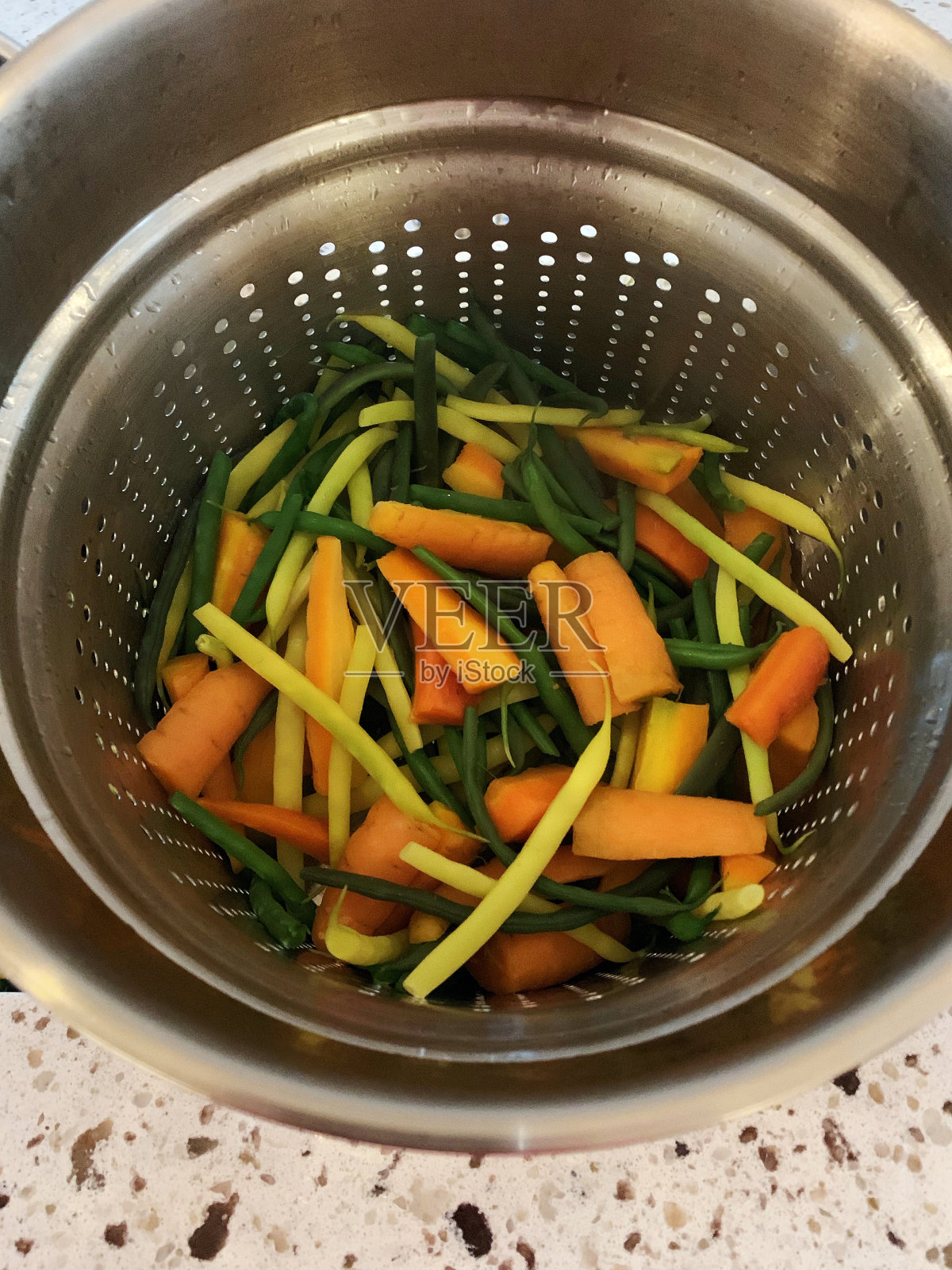 土生土长的新鲜收获的胡萝卜和混合豆子被切碎并在不锈钢滤锅中清洗照片摄影图片