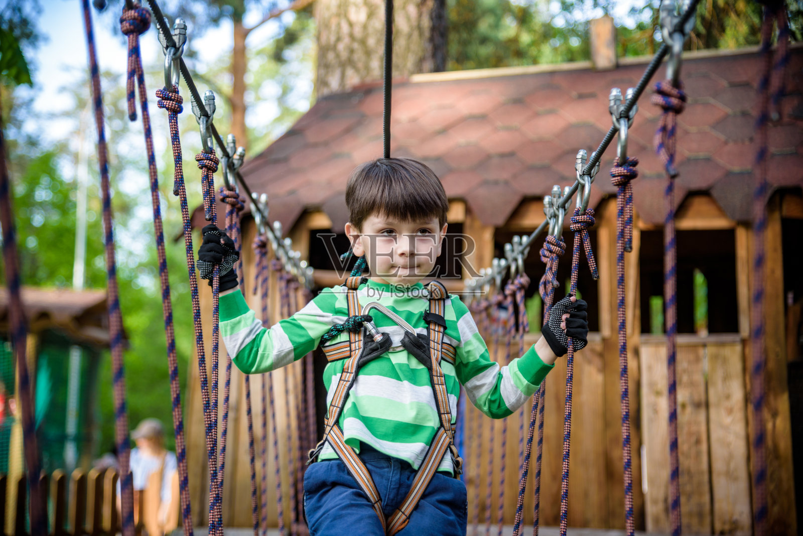 快乐的孩子在冒险公园玩，拿着绳子和爬木楼梯照片摄影图片