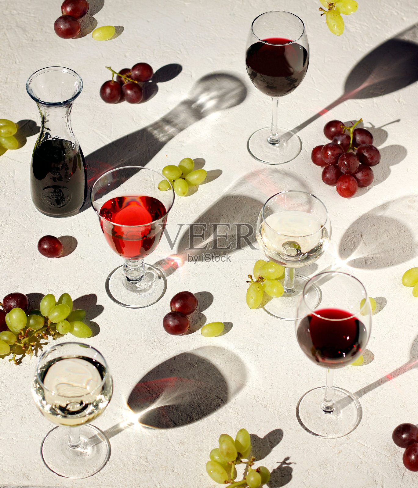 图案的葡萄酒杯装满了红、白、玫瑰葡萄酒和葡萄在不同的位置。照片摄影图片