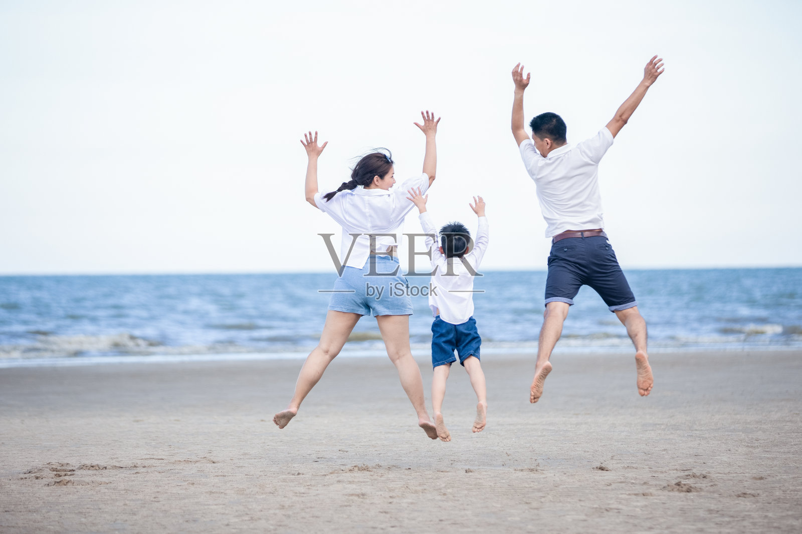 积极的父母和人在暑假和假期户外活动与孩子。幸福的家庭和儿子漫步在沙滩上的日落海的乐趣。照片摄影图片