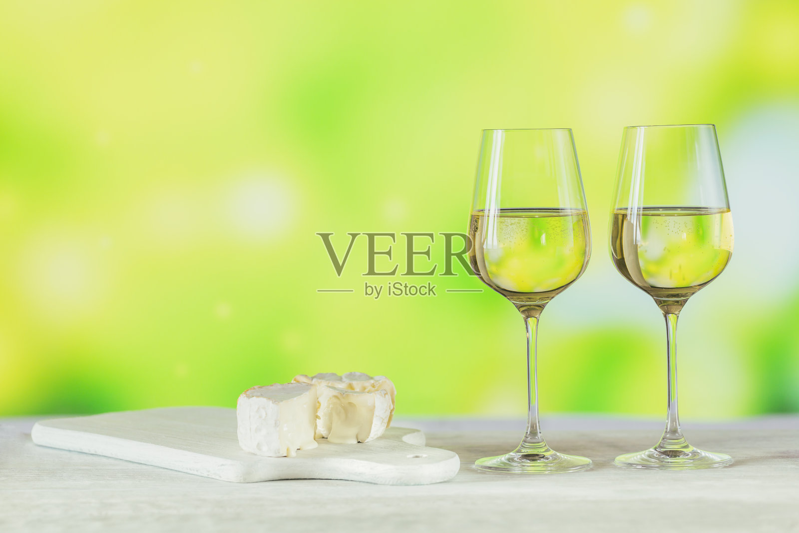 两杯白葡萄酒搭配浅绿色的芝士板。葡萄酒情绪概念照片摄影图片
