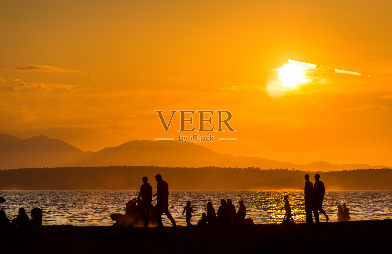 在夏天，美国西雅图的海滩上剪影的人日落的景象。照片摄影图片