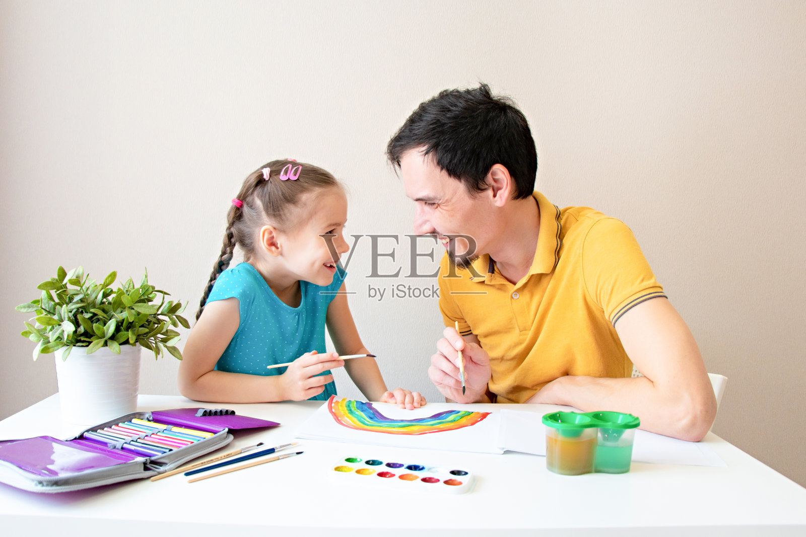 父女微笑，一起画一道彩虹。父亲和孩子玩得很开心。幸福的家庭。花更多的时间和你爱的人在一起照片摄影图片