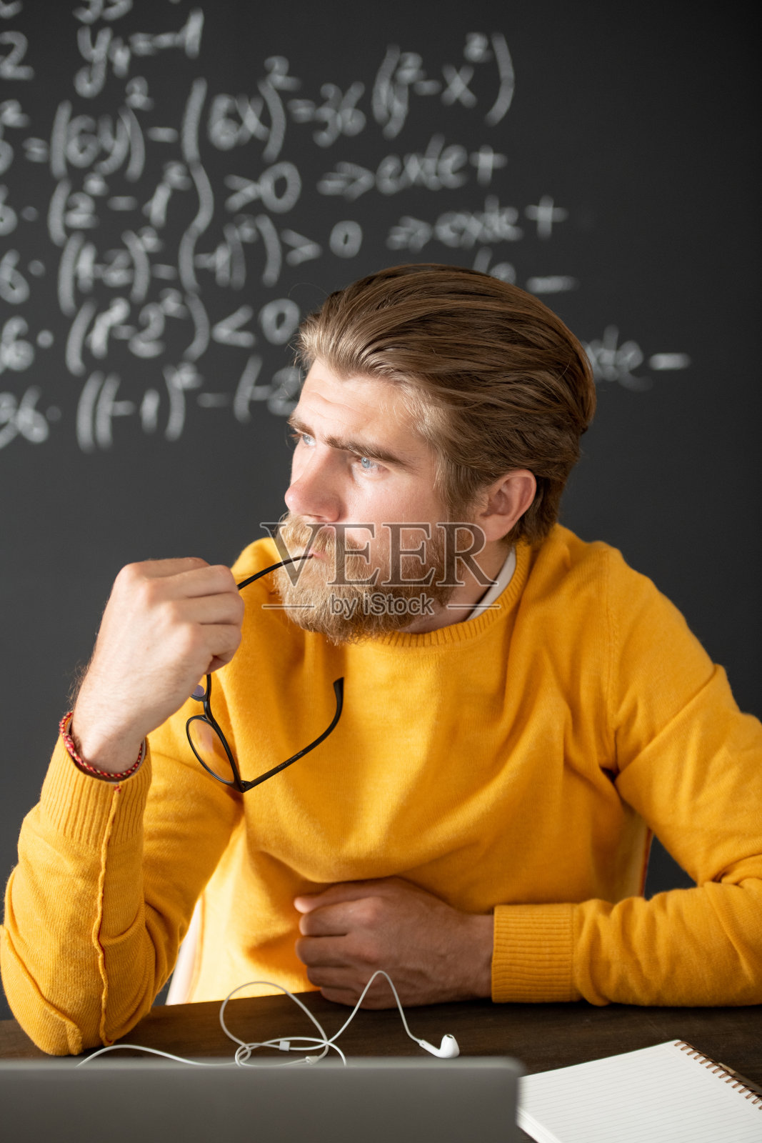 穿着黄色套衫的沉思老师在笔记本电脑前想着新讲座照片摄影图片