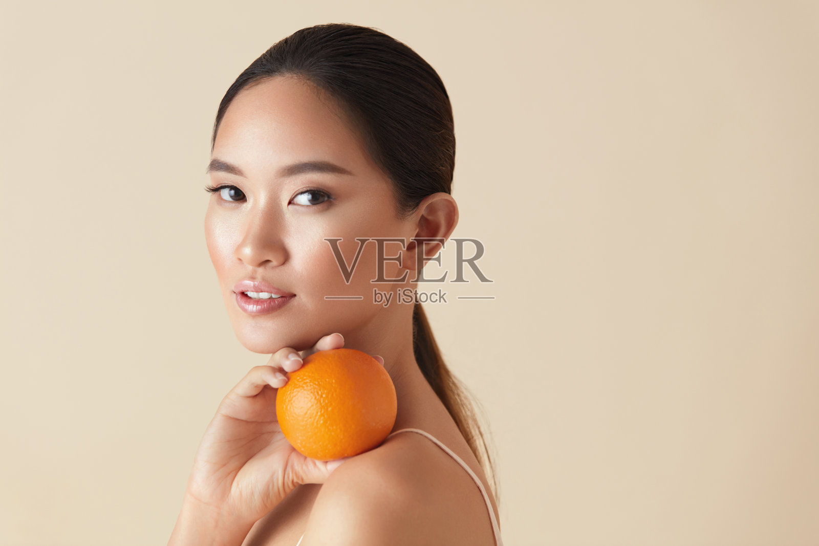 女人。美丽和水果肖像。亚洲模特抱着橘汁在她的肩膀上，看着相机。天然维生素为健康，容光焕发的面部皮肤和完美的身体。照片摄影图片