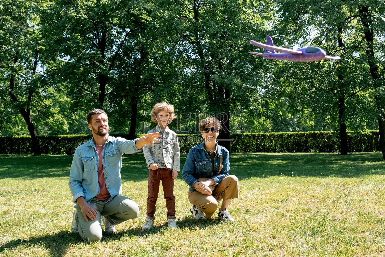 快乐的三口之家看着飞行的玩具飞机一起玩照片摄影图片