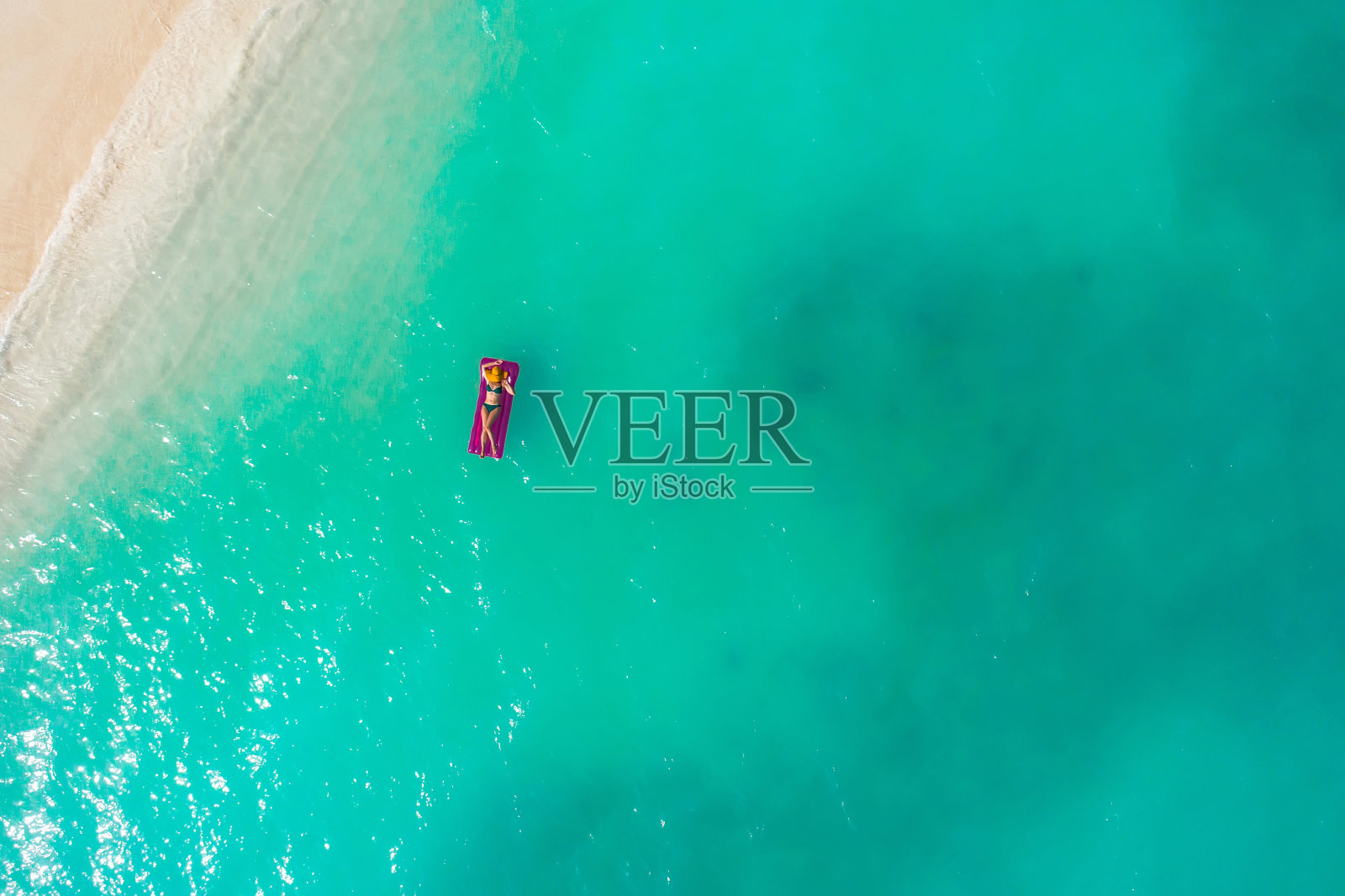 夏日假日的时尚概念——晒黑的女孩戴着太阳帽在沙滩上白沙滩上拍摄。俯视图从无人机。鸟瞰躺在马尔代夫海滩上晒太阳的苗条女人。照片摄影图片