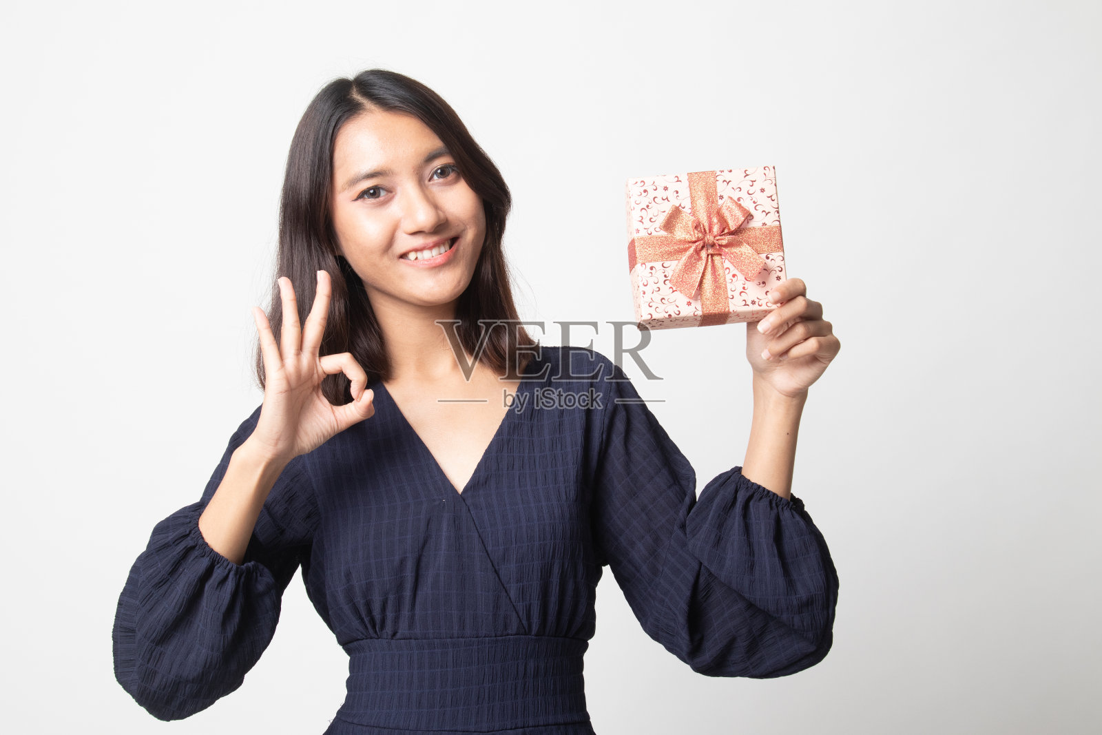 年轻的亚洲妇女显示OK与礼品盒。照片摄影图片