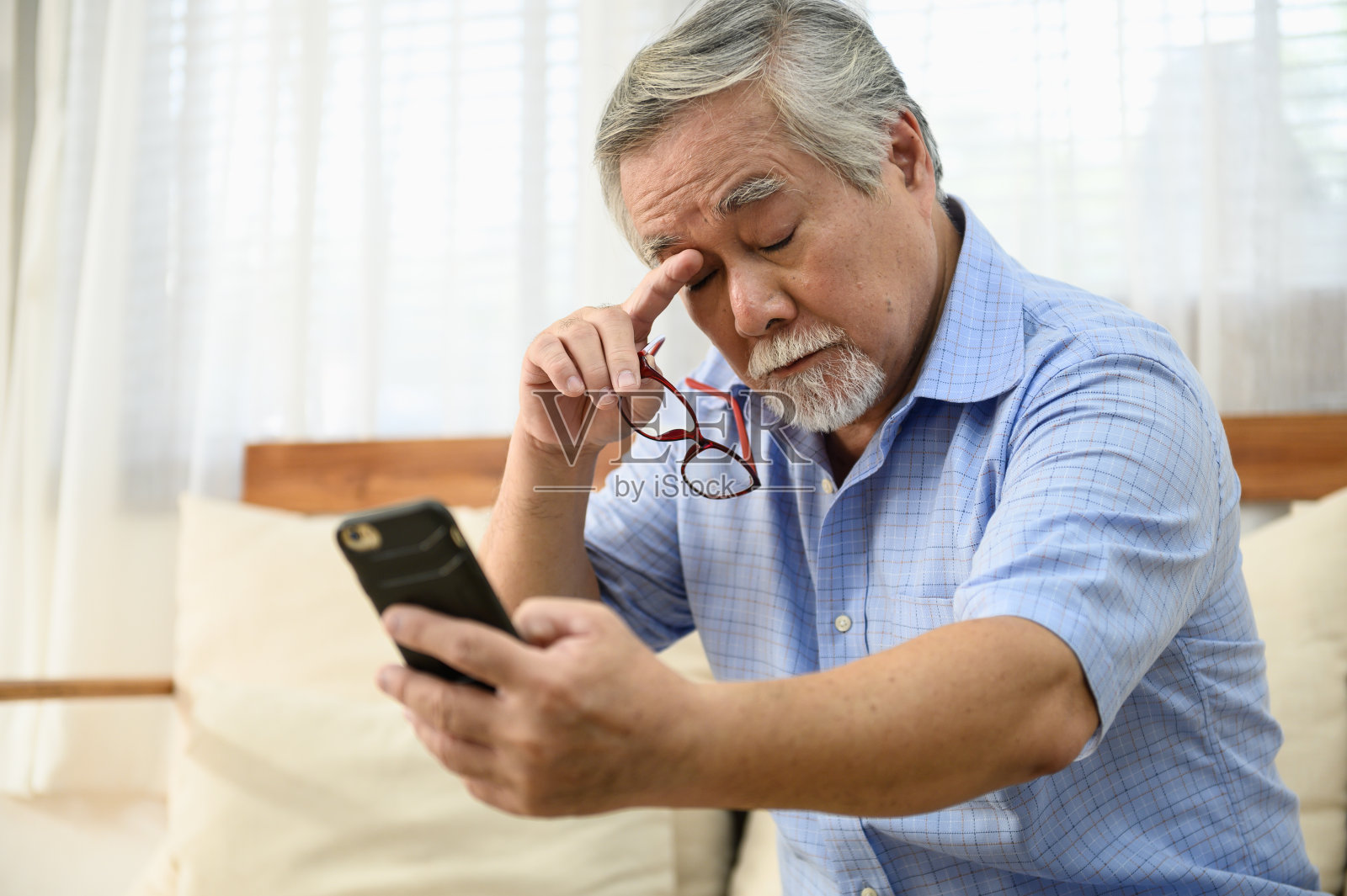 老年人生活方式健康问题概念:肖像照片的资深亚洲男子有一个眼睛远视问题，试图阅读智能手机的信息。照片摄影图片