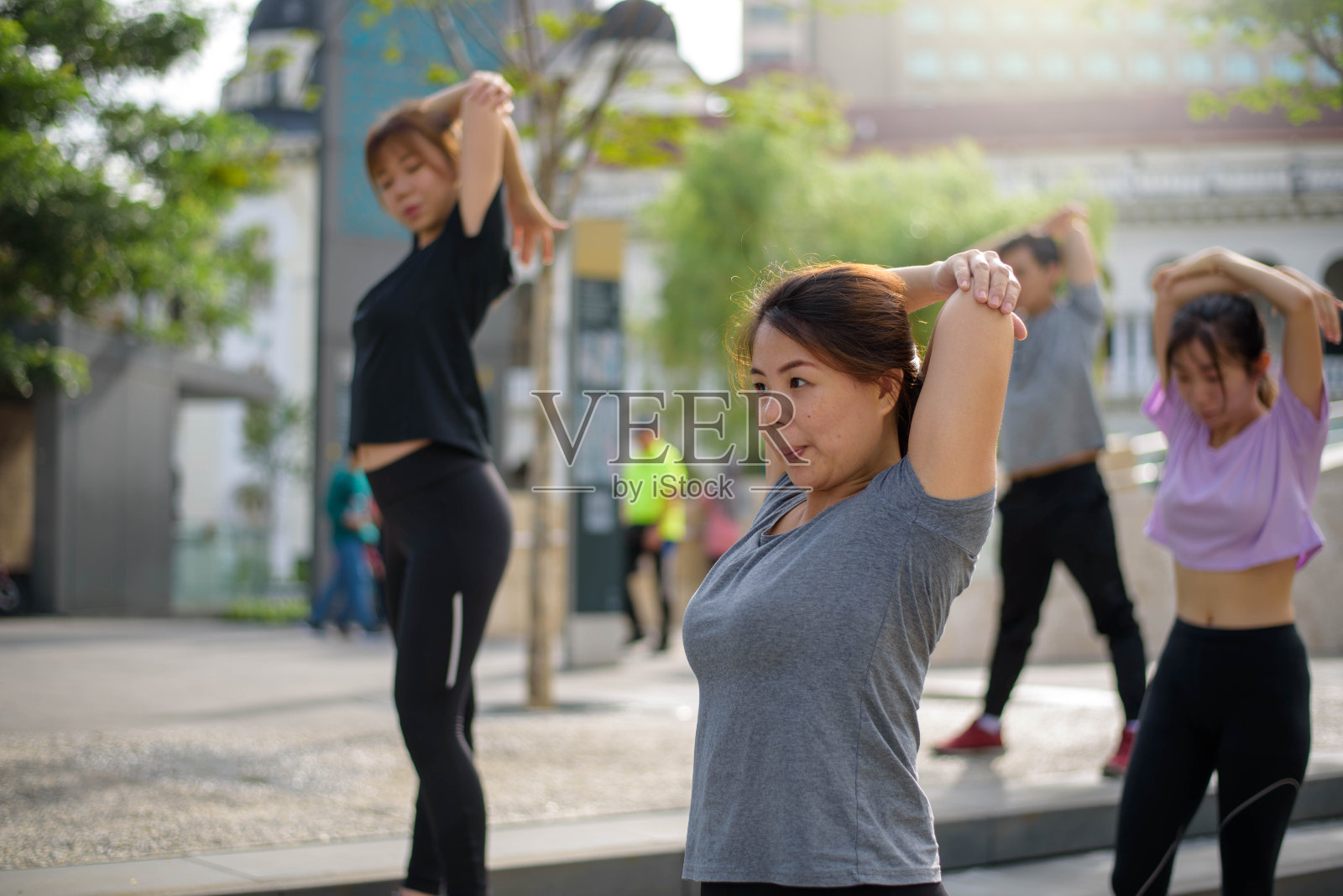 一个亚洲女人和她的朋友在运动服装热身和伸展在户外人行道上锻炼照片摄影图片