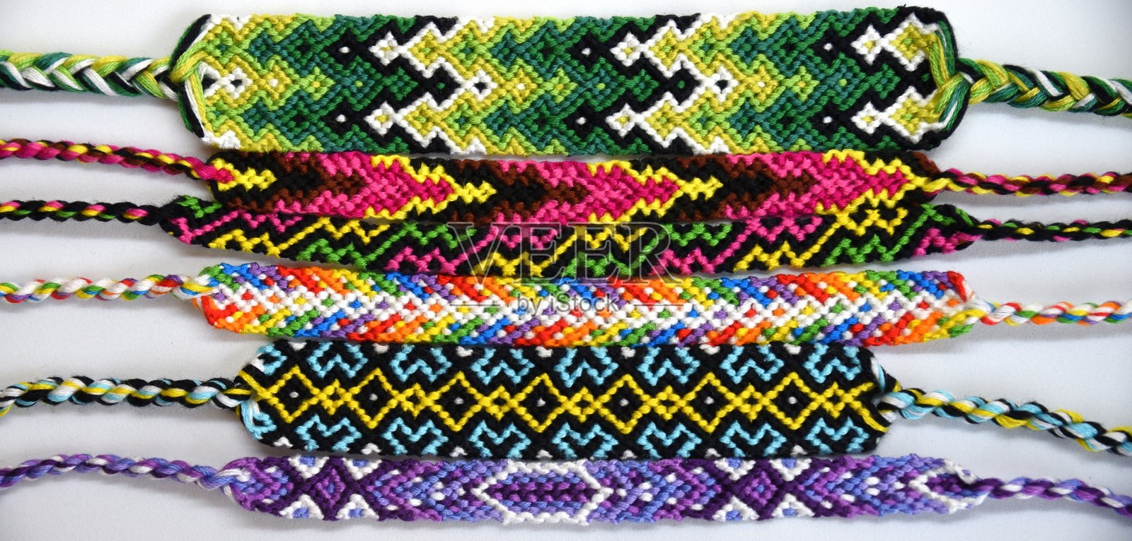许多手工编织的手工编织的友谊手链，绣亮线与结在光线的背景。照片摄影图片