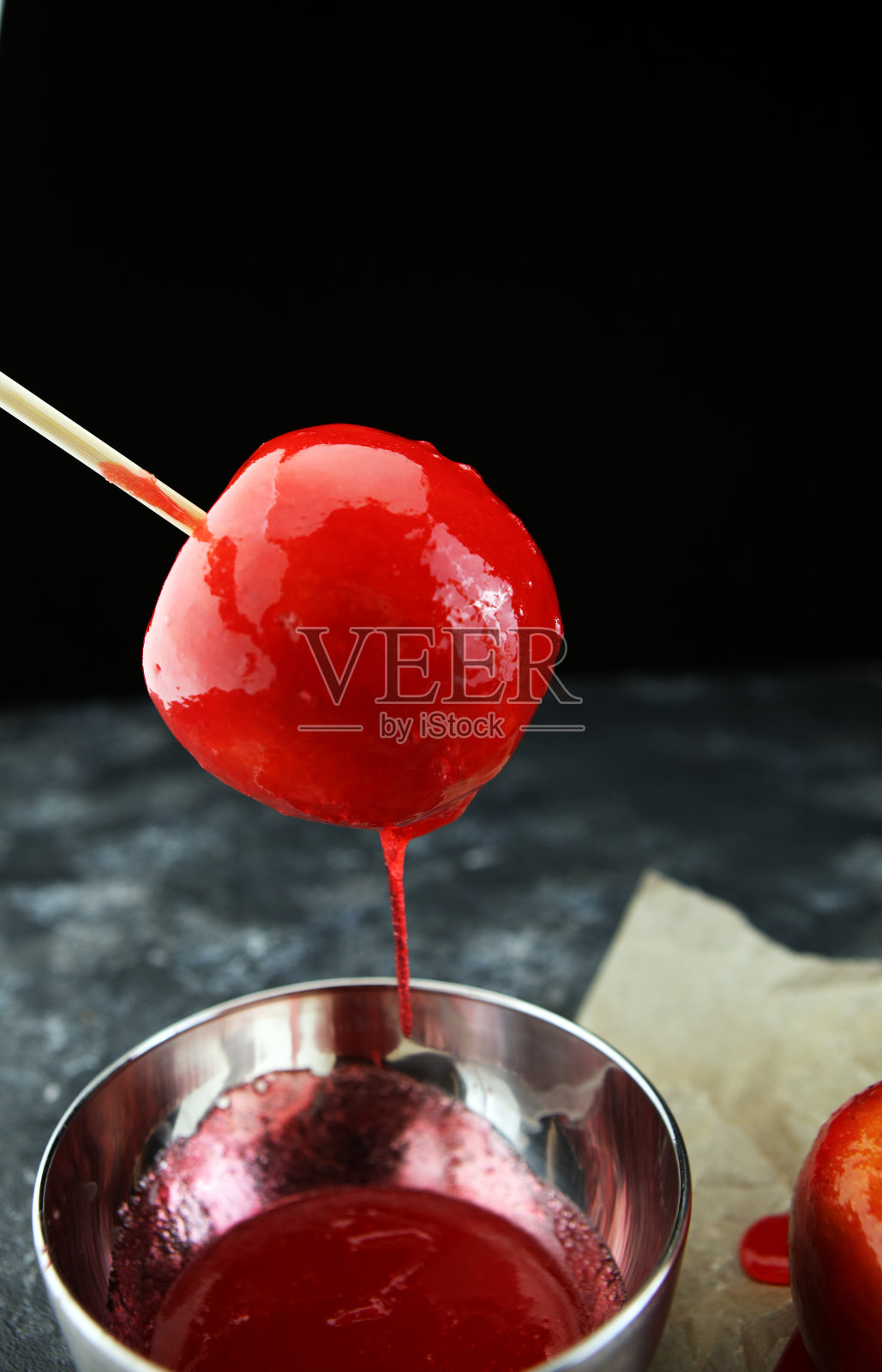 在农贸市场或乡村集市上为孩子们出售的甜的红色糖霜太妃糖苹果棒。照片摄影图片