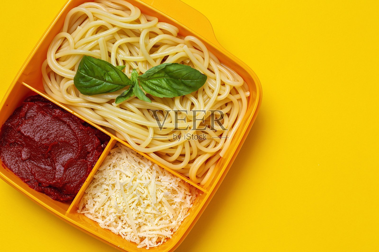 装在塑料容器里的健康食品，可与意大利面、番茄、奶酪和罗勒一起食用照片摄影图片