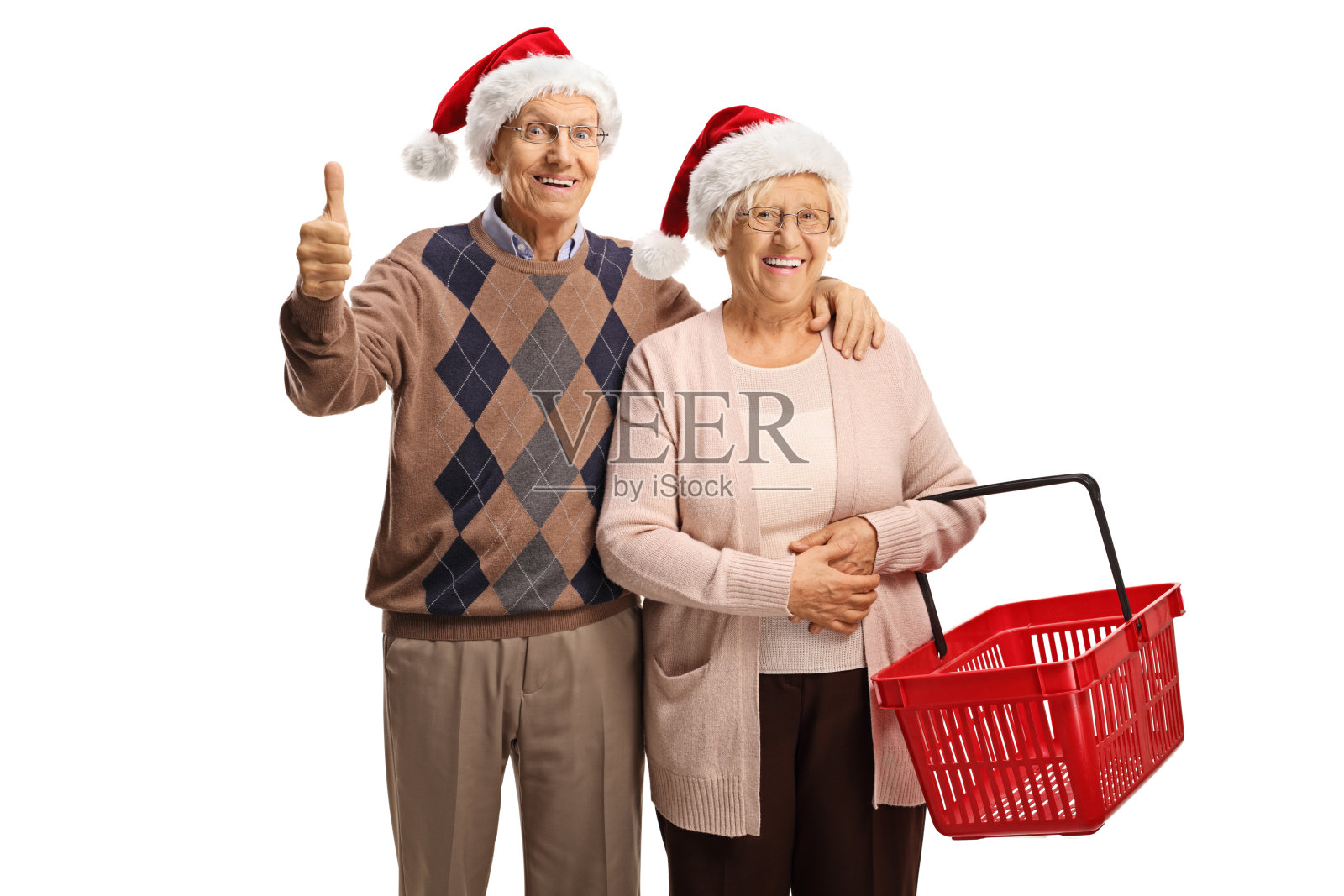 拿着购物篮的老夫妇戴着圣诞老人帽，竖起大拇指照片摄影图片