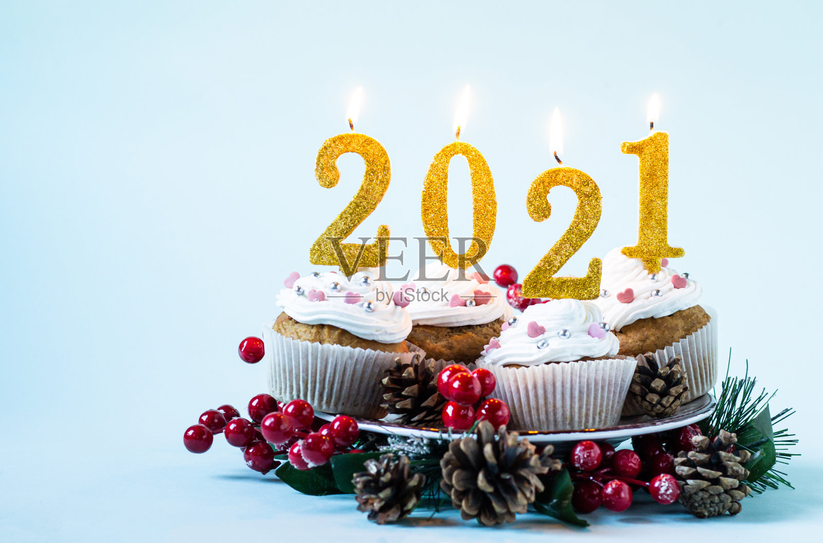 2021年新年快乐纸杯蛋糕和点燃的蜡烛。圣诞快乐，冬季问候概念。本空间照片摄影图片