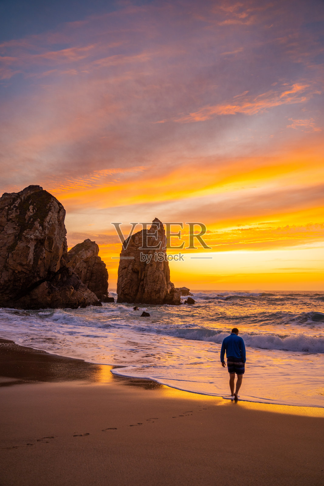 葡萄牙普拉亚·达·乌尔萨，日落时分沙滩上的男人照片摄影图片