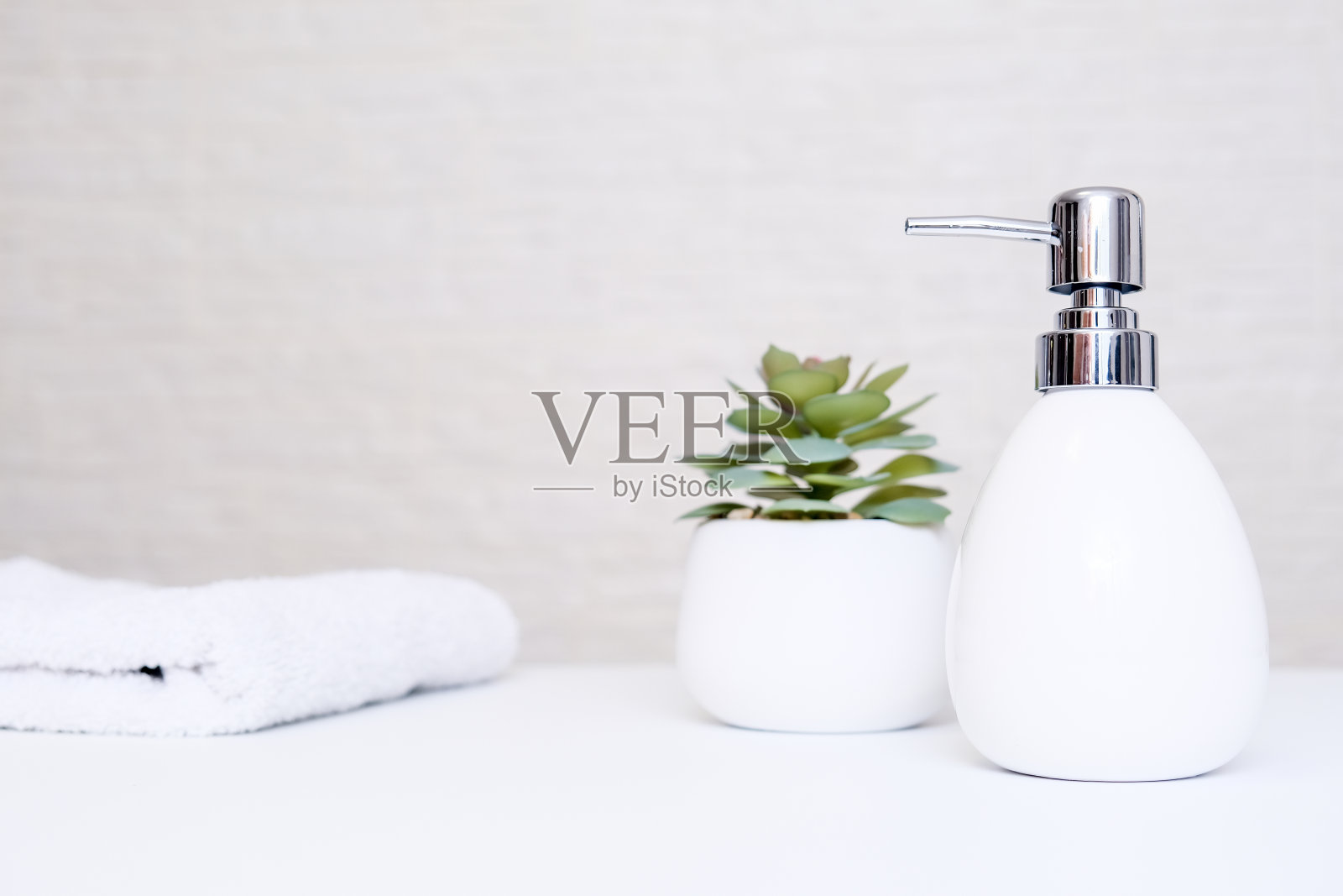 水疗沙龙和浴室内部颜色柔和，灰色的肥皂机，白色的毛巾和盆栽植物为水疗，身体和面部护理照片摄影图片