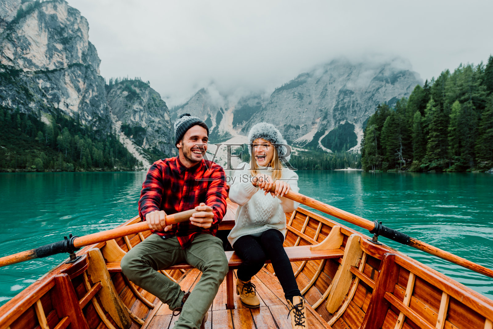 一对浪漫的情侣在小船上游览意大利的布雷斯的一个高山湖。相爱的游客一起在秋天的山上度过相爱的时刻。关于旅行、情侣和旅游的概念。照片摄影图片