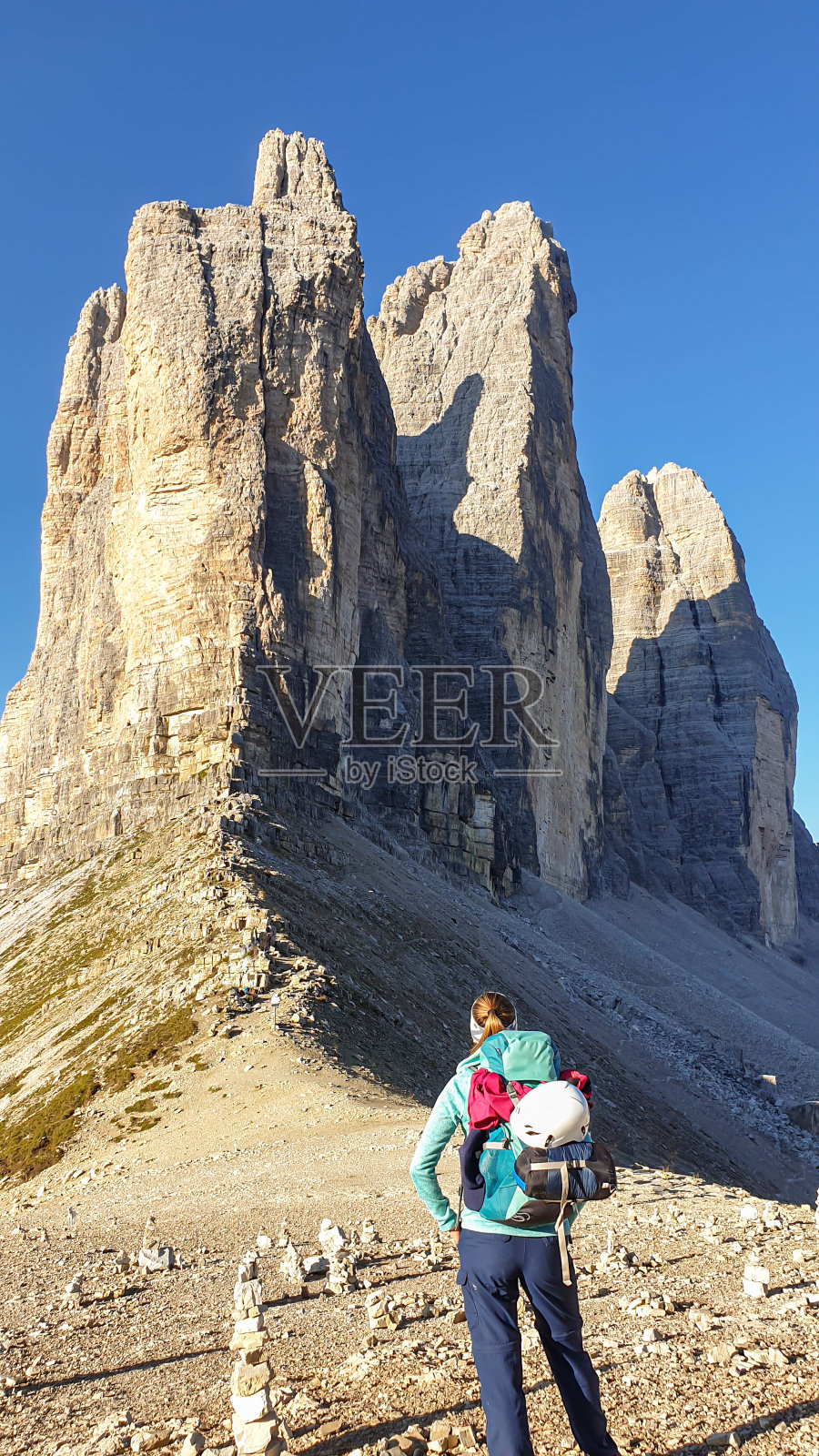 一位背着大背包的妇女正在欣赏意大利Dolomites地区的Drei Zinnen山的近景。尖锐而高大的山墙。荒凉和原始的景观。照片摄影图片