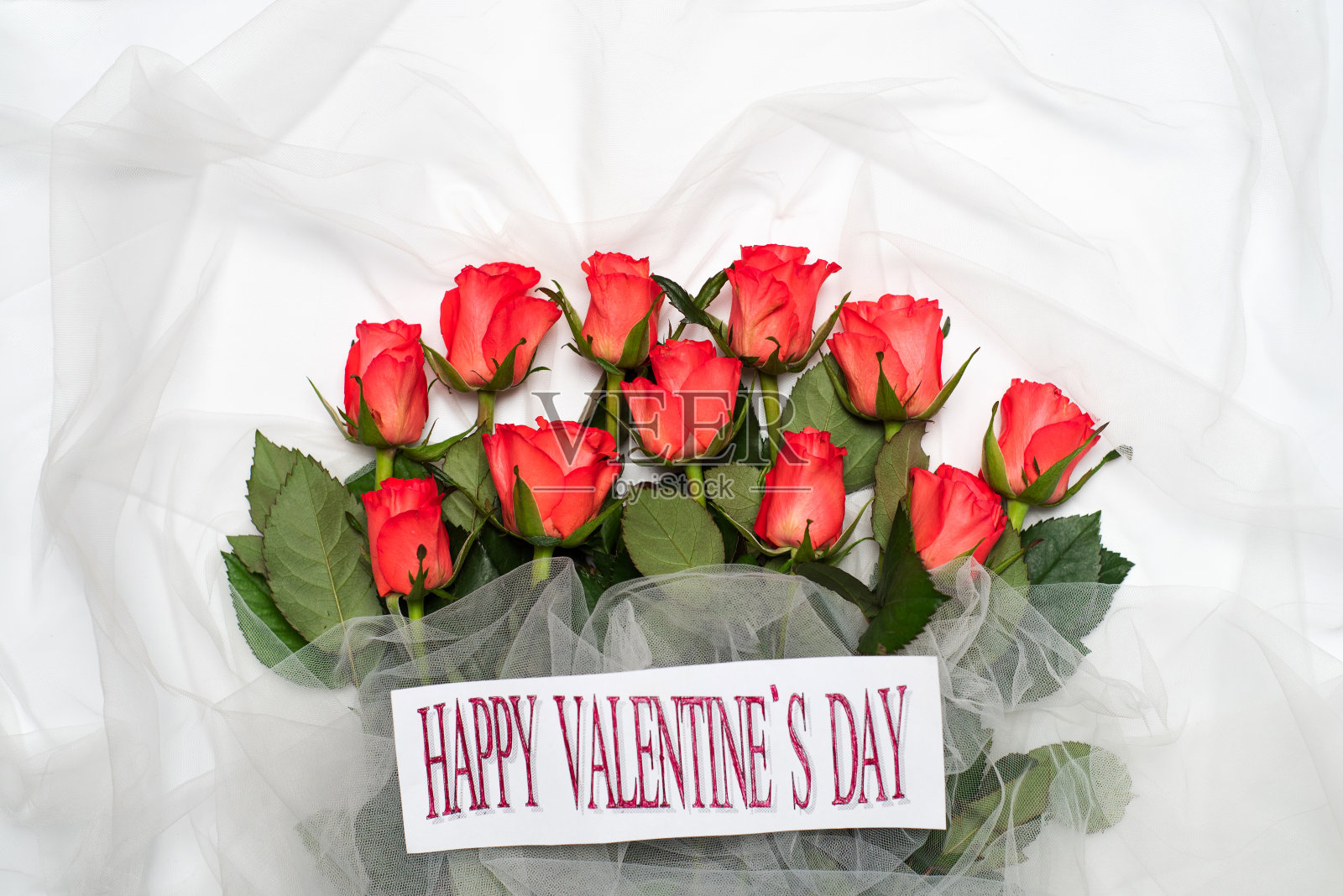红玫瑰花束在白色织物上与情人节贺卡照片摄影图片