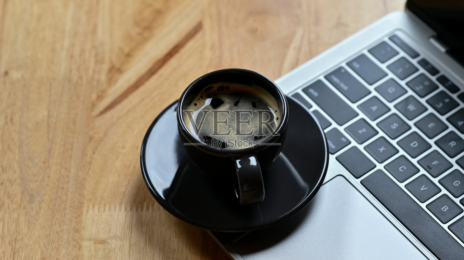 这是热咖啡放在笔记本电脑键盘上的特写镜头。照片摄影图片