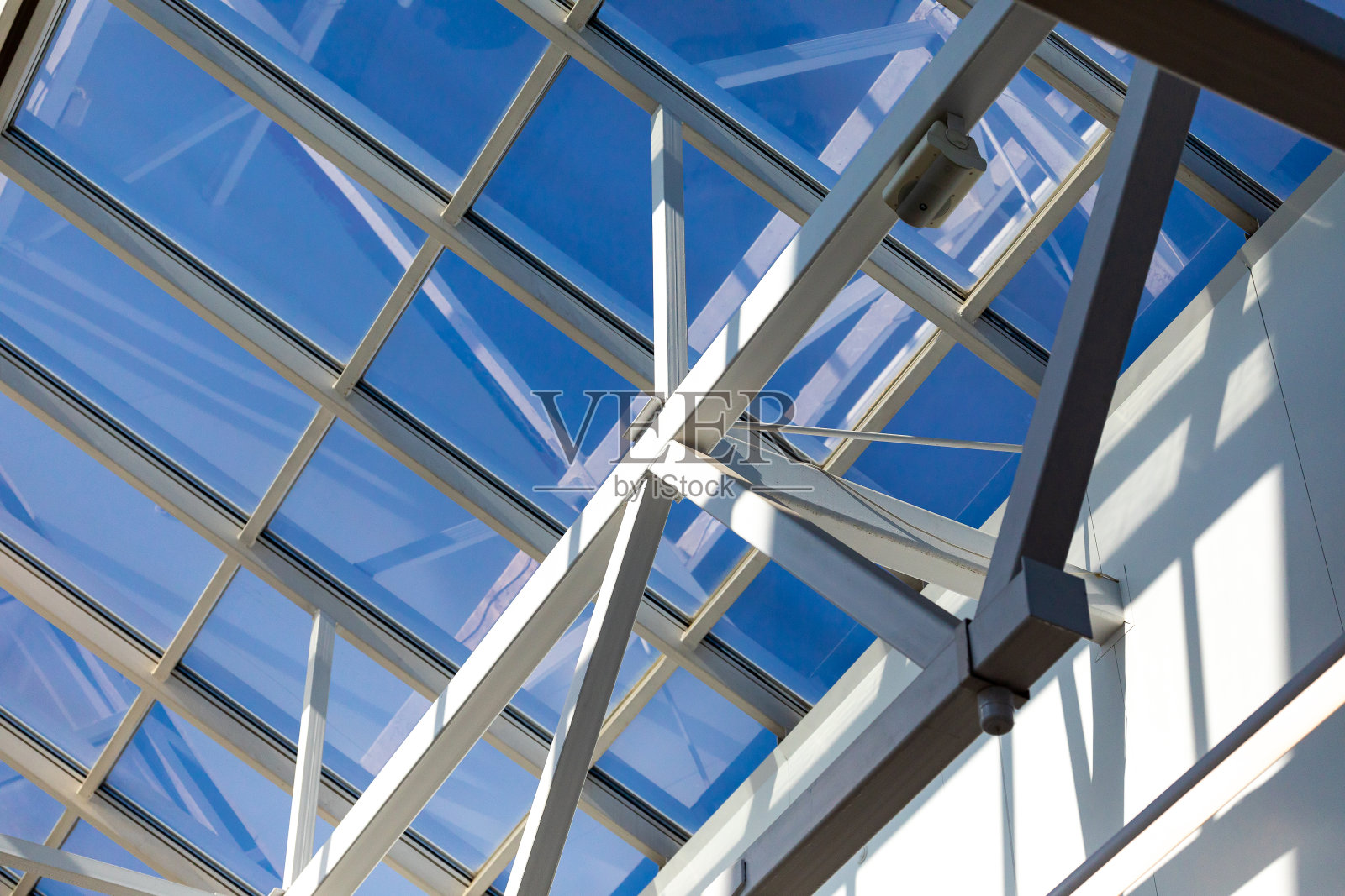 仓库、商场或办公中心的玻璃屋顶的钢框架。天花板由金属梁组成，通过螺栓和焊接连接，以保持流动性和刚性。照片摄影图片