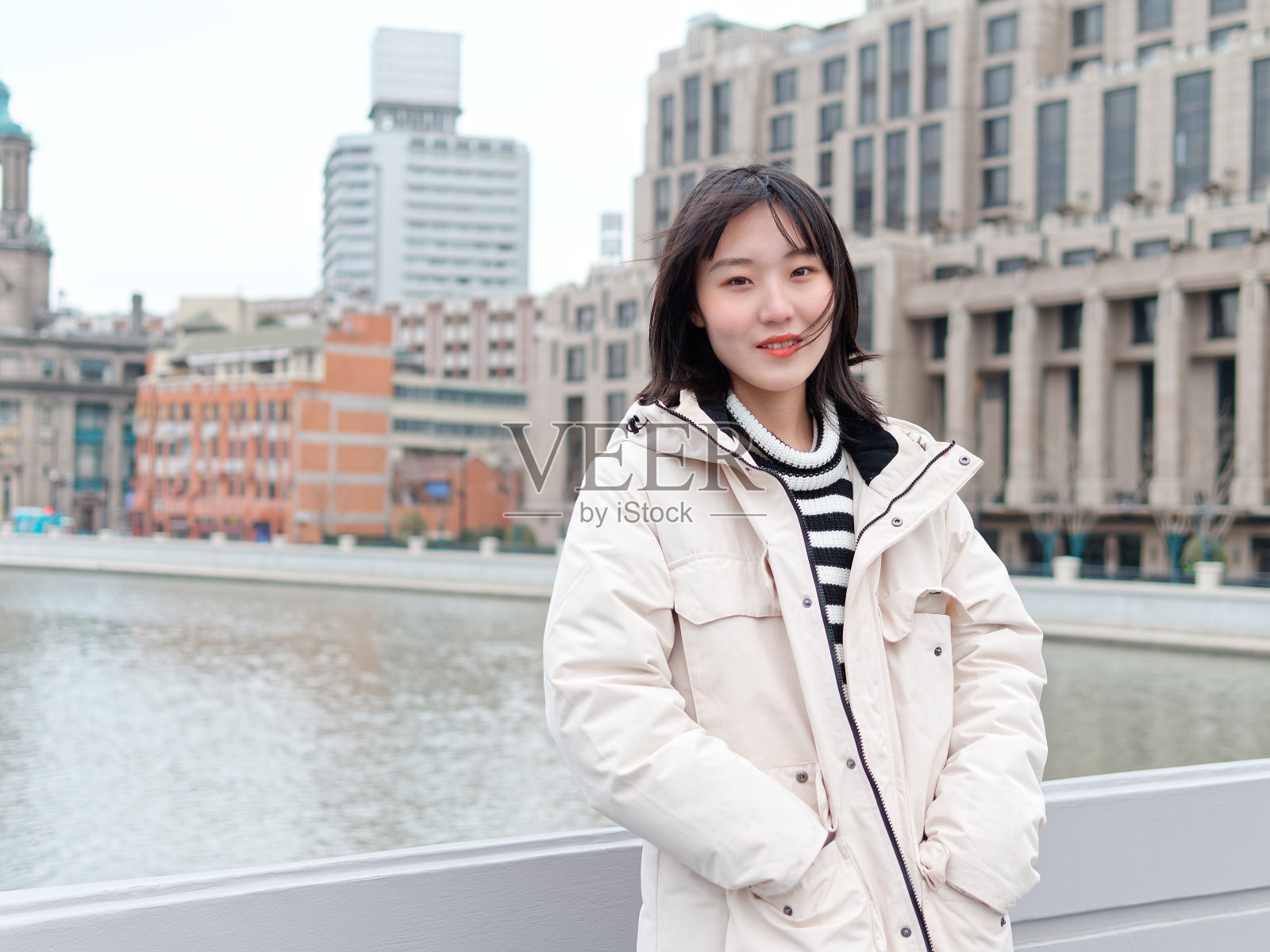 冬日里以上海地标为背景的中国年轻女子的肖像。照片摄影图片