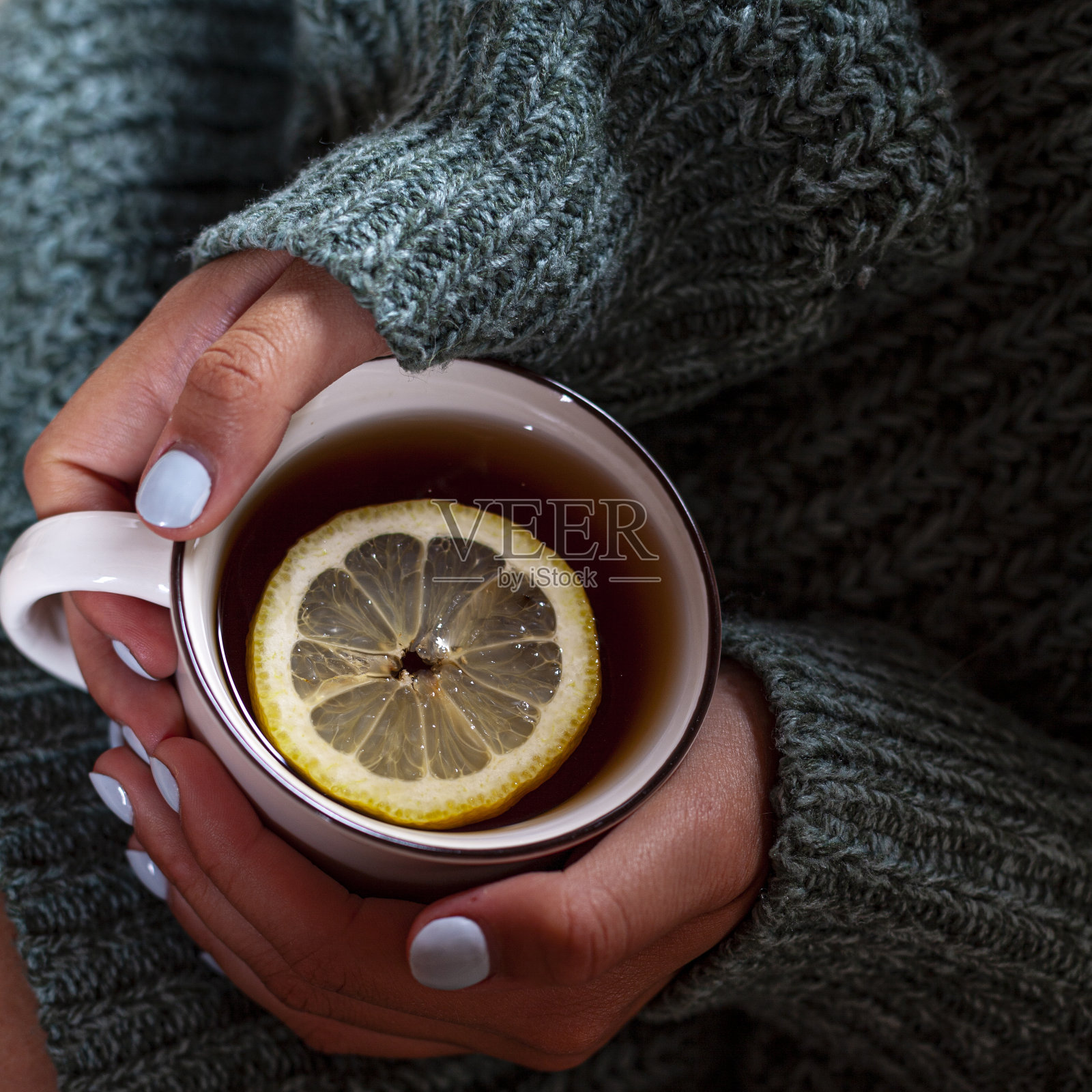 清晨女性手捧一杯柠檬热茶。照片摄影图片