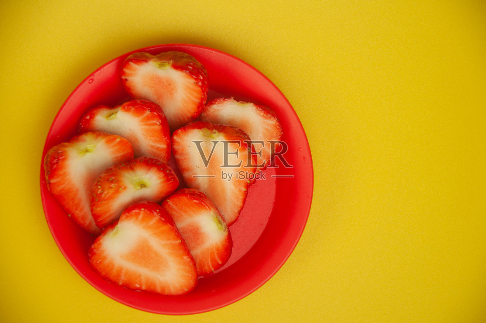 草莓躺在一个红色的盘子里照片摄影图片
