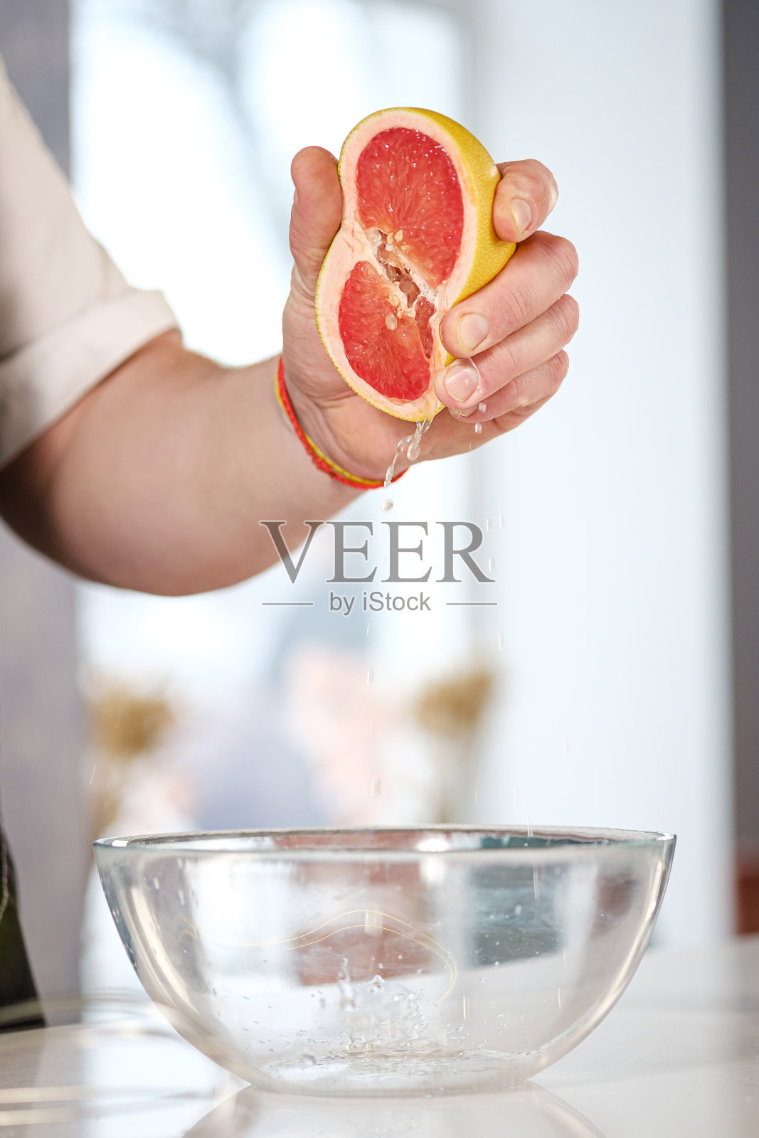 男厨师厨师的手的特写，从一半的葡萄柚榨汁。照片摄影图片