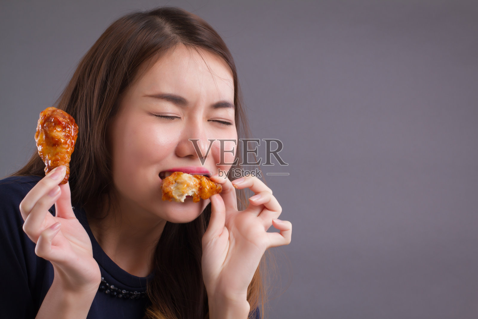 女人吃不健康的肥肉炸鸡;写照不健康女孩吃肥肉炸鸡、快餐;不健康饮食，以高胆固醇高脂肪的饮食观念;亚洲华人20多岁的女性模特照片摄影图片
