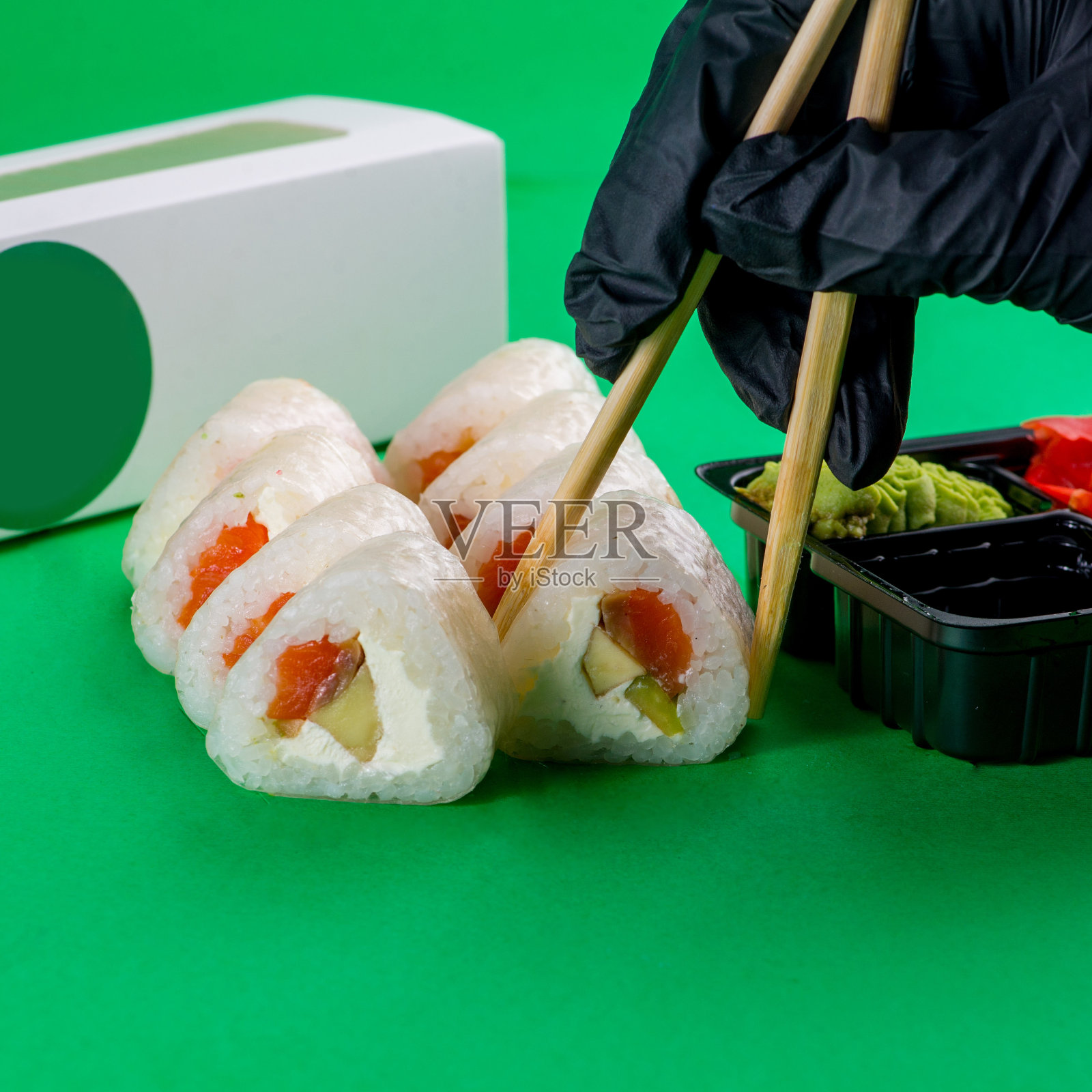 蘸酱的寿司是用筷子吃的。白色寿司，奶油芝士，绿色背景照片摄影图片