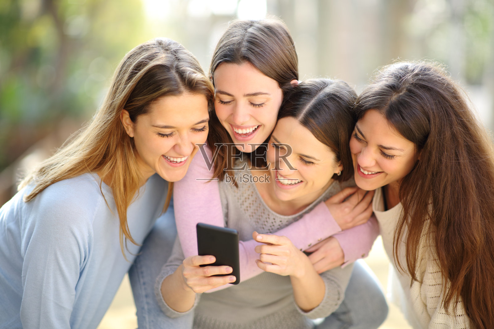 四个开心的女人在看手机里的内容照片摄影图片