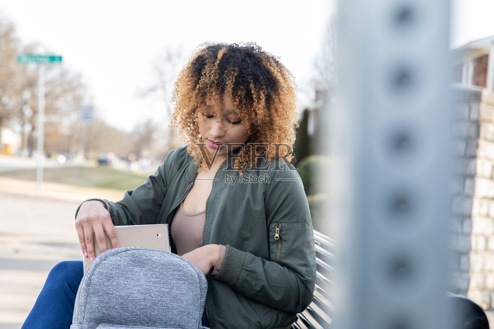 年轻的黑人妇女是一名大学生，在校园里等候公共交通工具，在她去上大学的路上照片摄影图片