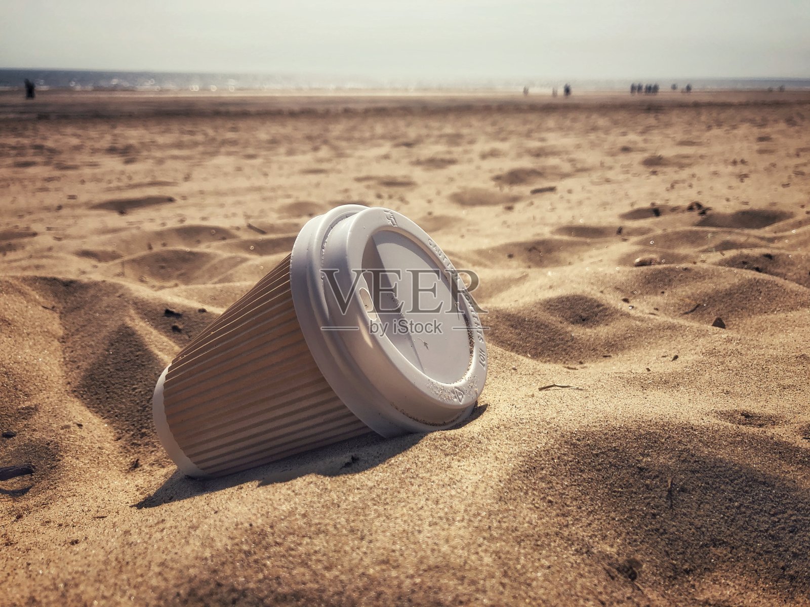 丢弃在沙滩上的一次性外卖咖啡杯照片摄影图片