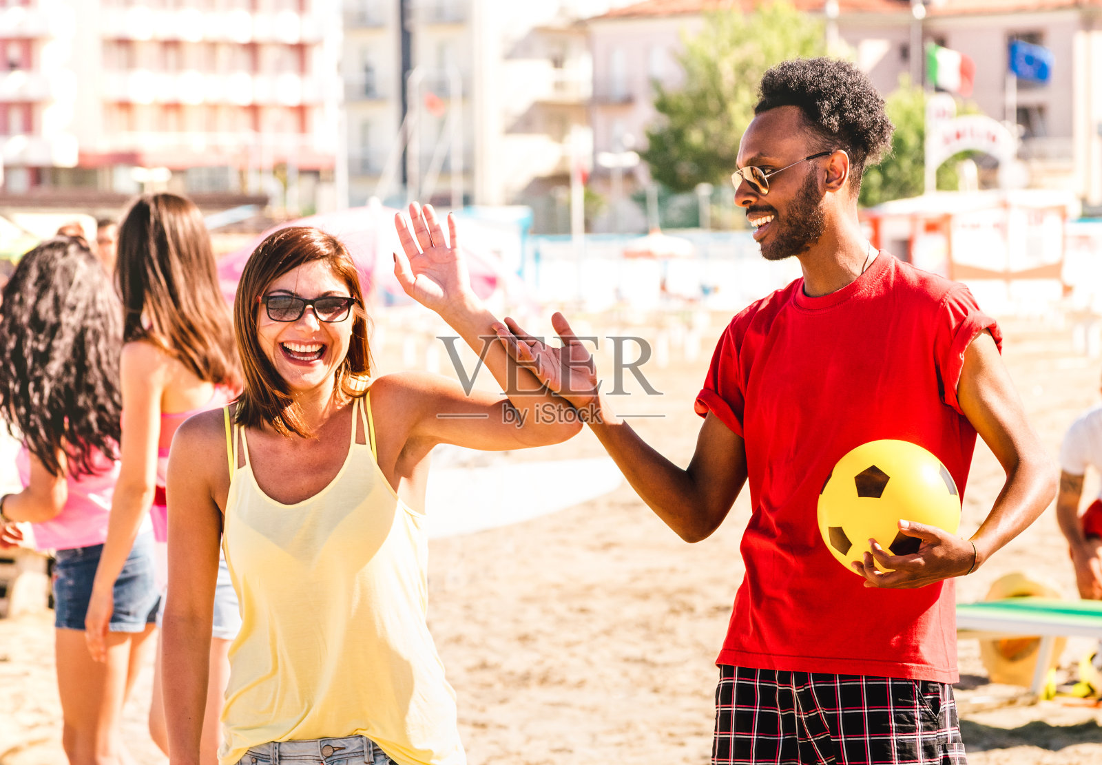 多种族的夫妇准备在阳光明媚的一天玩沙滩足球-暑假概念和多文化的友谊与男孩和女孩一起有乐趣-明亮的温暖过滤器与焦点对男人照片摄影图片