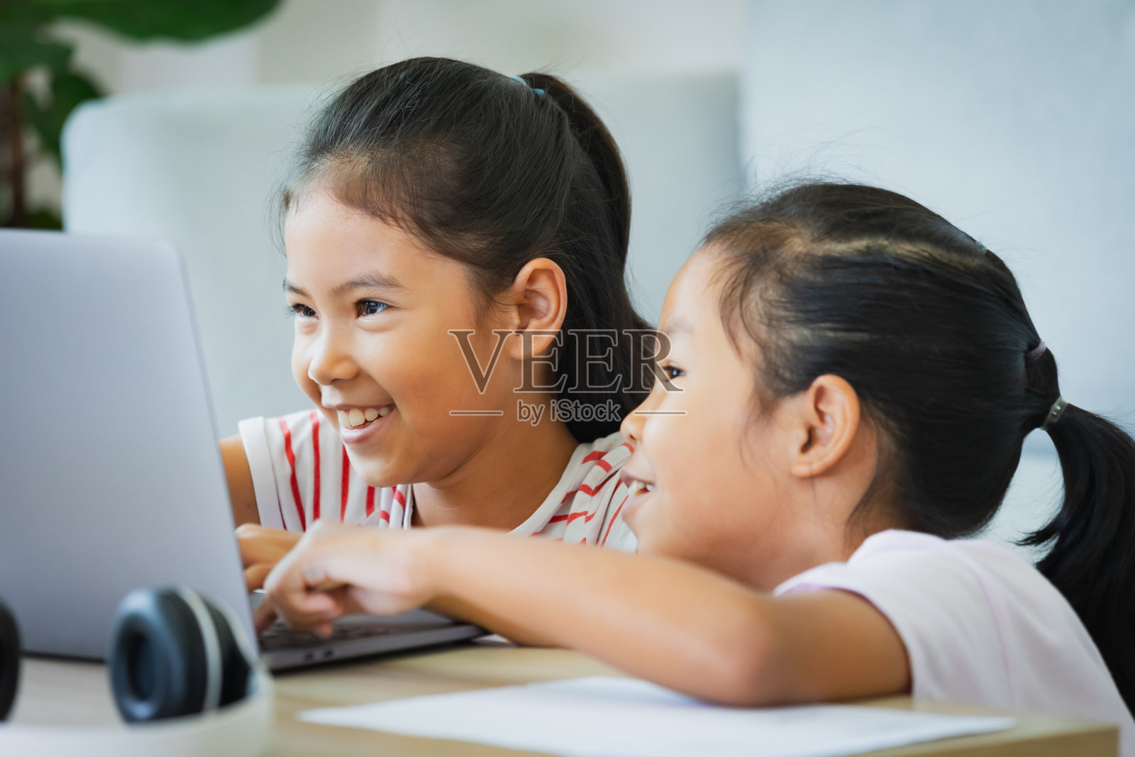 两名亚洲女童学生通过视频一起与老师在线学习。由于Covid - 19大流行，兄弟姐妹在隔离期间用电脑在家学习。照片摄影图片