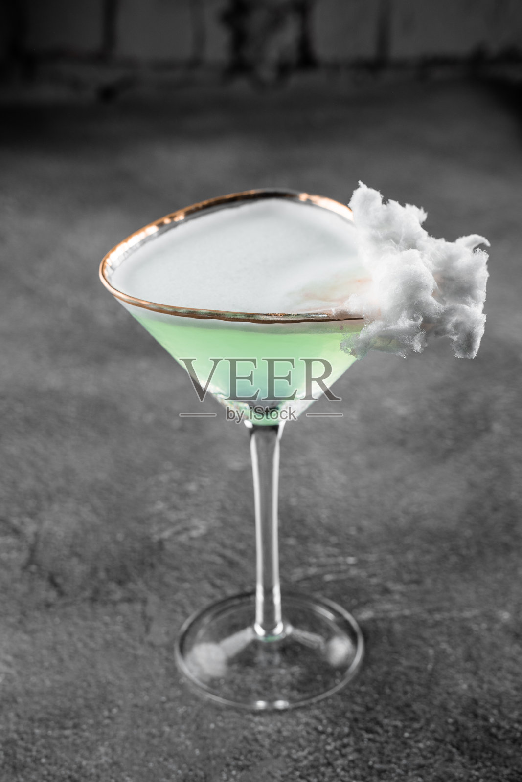 灰色背景上装饰着棉花糖的绿色酒精鸡尾酒。照片摄影图片