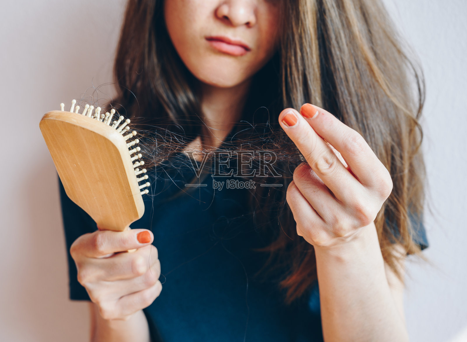 剪短的照片，担心的女人拿着梳子与头发丢失后梳理她的头发。照片摄影图片