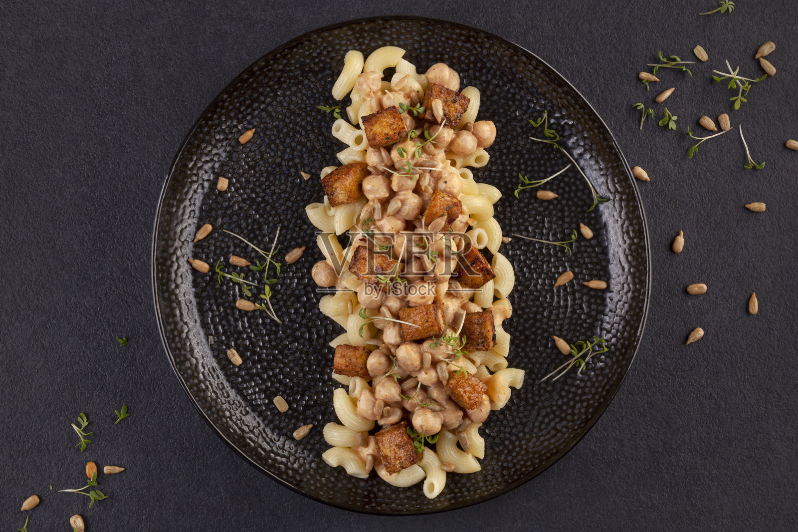 美味的意大利面，鹰嘴豆，豆腐和新鲜的香草从上面的深色背景。照片摄影图片