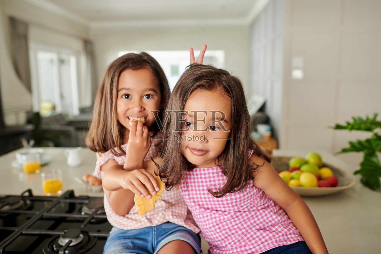 两个可爱的姐妹在家里的厨房柜台上吃煎饼照片摄影图片