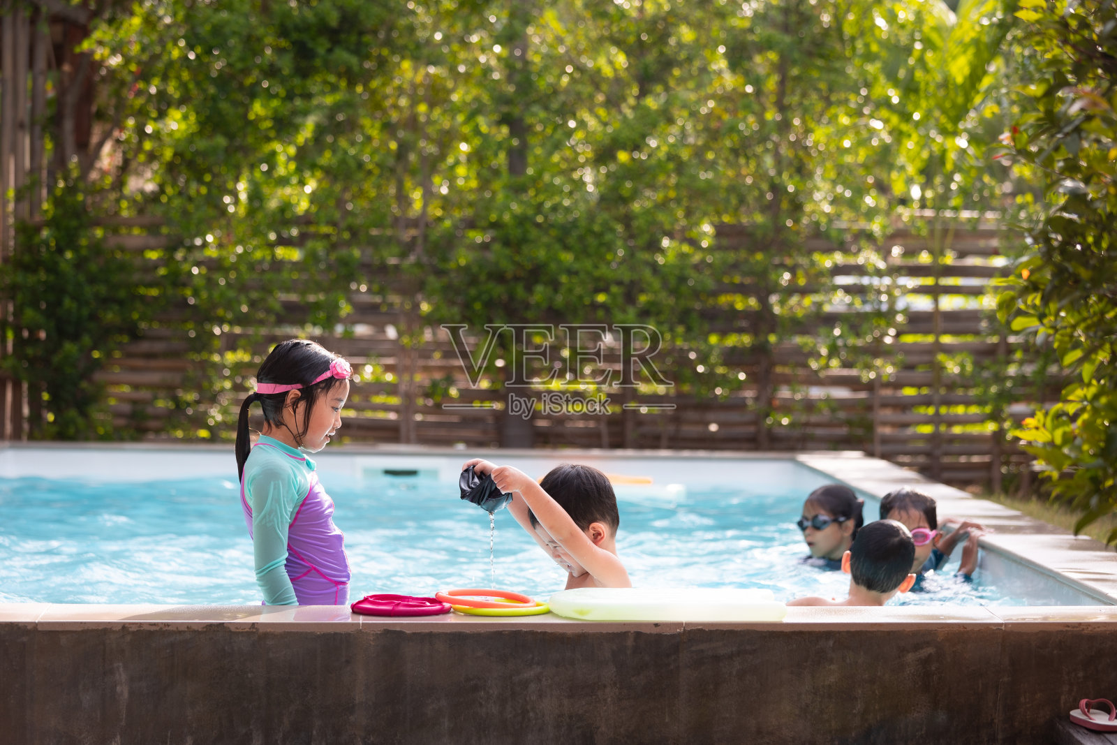 亚洲儿童女孩和男孩一起在游泳池玩水和游泳的乐趣。照片摄影图片