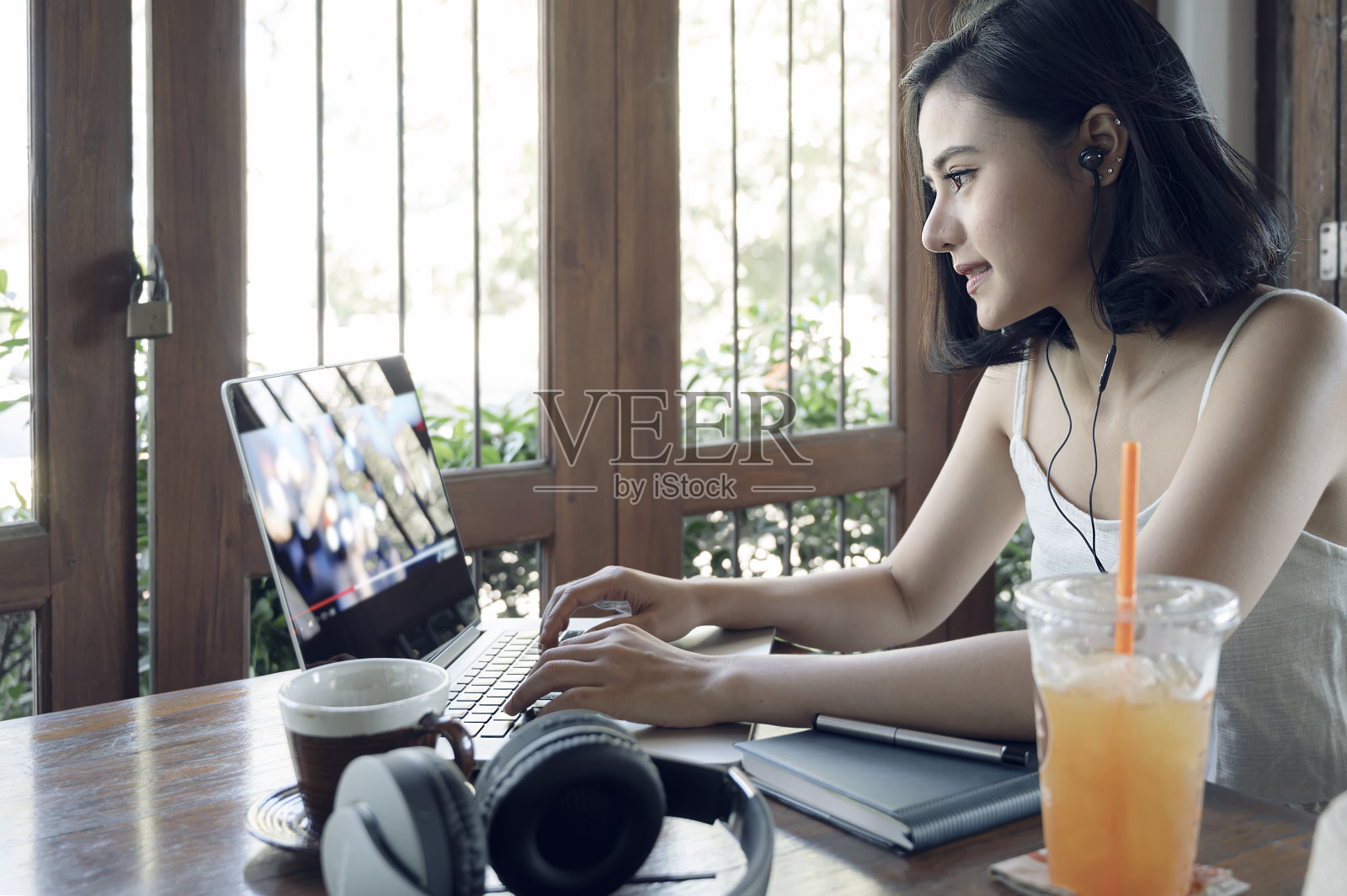 年轻美丽的亚洲女人使用笔记本电脑在网上工作，而呆在家里。照片摄影图片