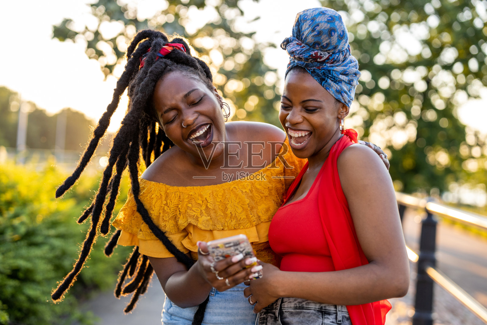 两个女性朋友拿着智能手机，在户外微笑照片摄影图片